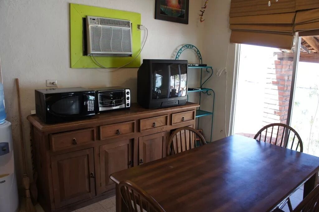 A kitchen with a microwave, a television, and a cabinet.