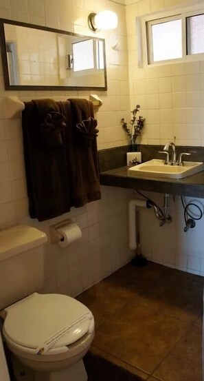 A small bathroom with a toilet, sink, and mirror.