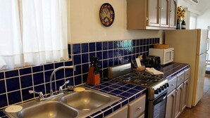 Cozinha com azulejos azuis, eletrodomésticos de aço inoxidável e armários de madeira.