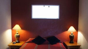 Quarto com cama, duas mesas de cabeceira, duas luminárias e uma janela.