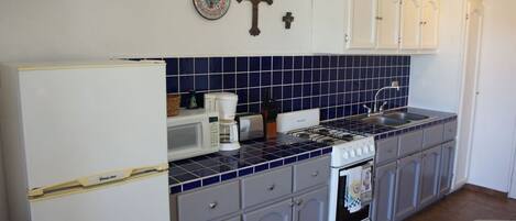 A kitchen with white cabinets, a stove, a sink, and a microwave.