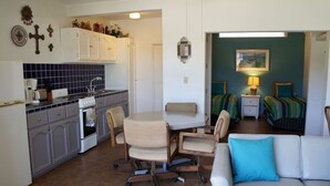 A compact living space with a kitchenette, dining area, and a bedroom with two beds.