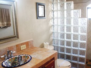 A bathroom with a tiled sink, a mirror, a toilet, and a shower with frosted glass panels. - Costa del Mar 57 2 Bedroom Apartment By Seaside San Carlos (San Carlos)