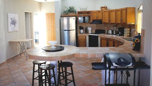 A modern kitchen with a central island, bar stools, a built-in grill, and a skylight. - Costa del Mar 57 2 Bedroom Apartment By Seaside San Carlos (San Carlos)