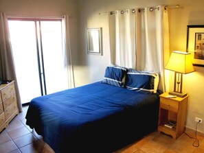 A bedroom with a bed, a nightstand, a lamp, a dresser, and a window with curtains. - Costa del Mar 57 2 Bedroom Apartment By Seaside San Carlos (San Carlos)