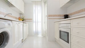 Een moderne keuken met witte kasten, een inbouwoven en een wasmachine.