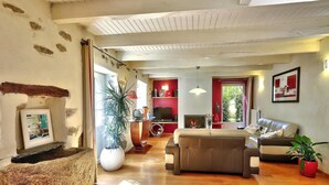 Un salon spacieux doté d’une cheminée, de parquet et d’une grande fenêtre laissant entrer la lumière naturelle.