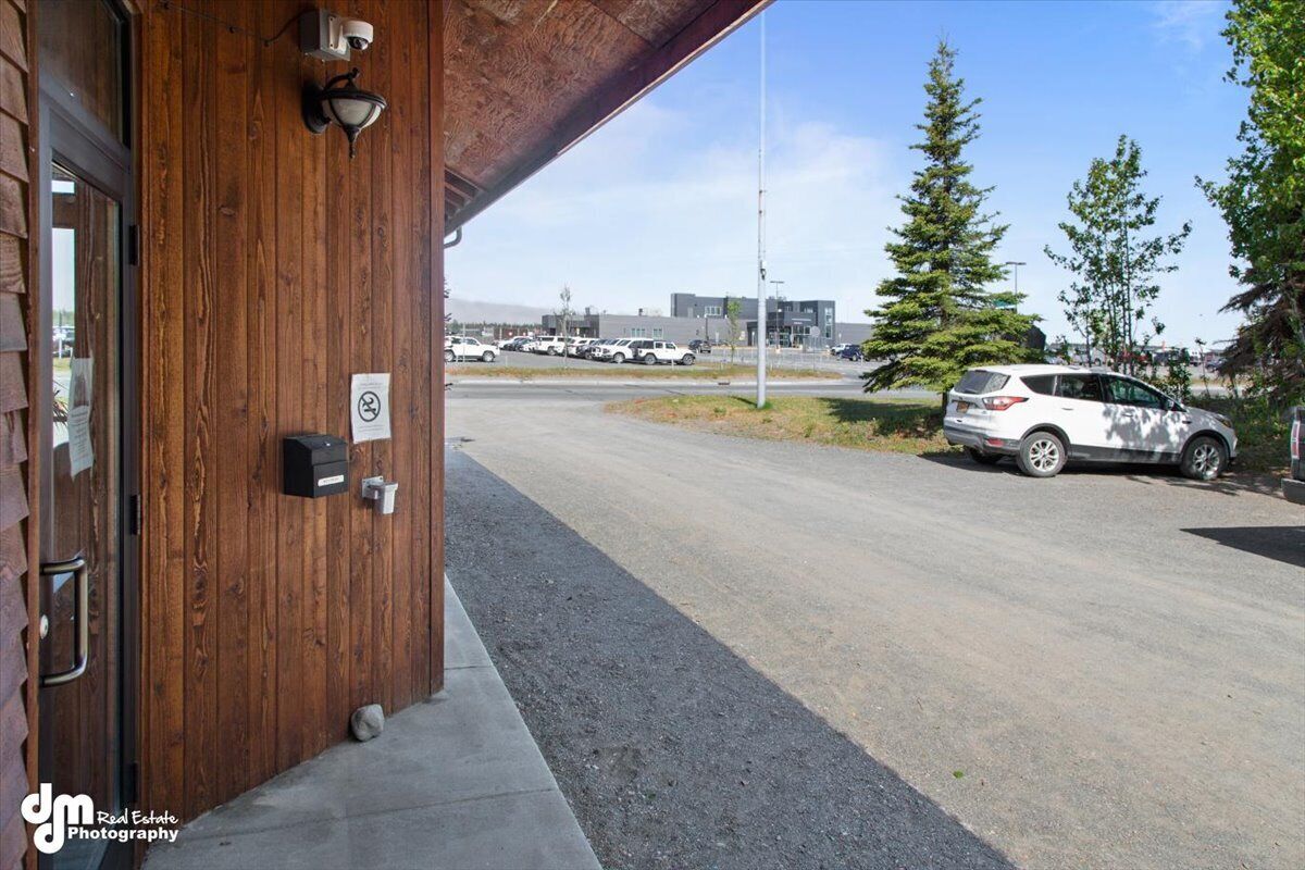 Un edificio con fachada de madera, una puerta visible y un estacionamiento con automóviles.