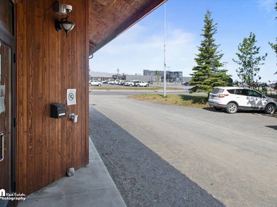 Un edificio con fachada de madera, una puerta visible y un estacionamiento con automóviles.