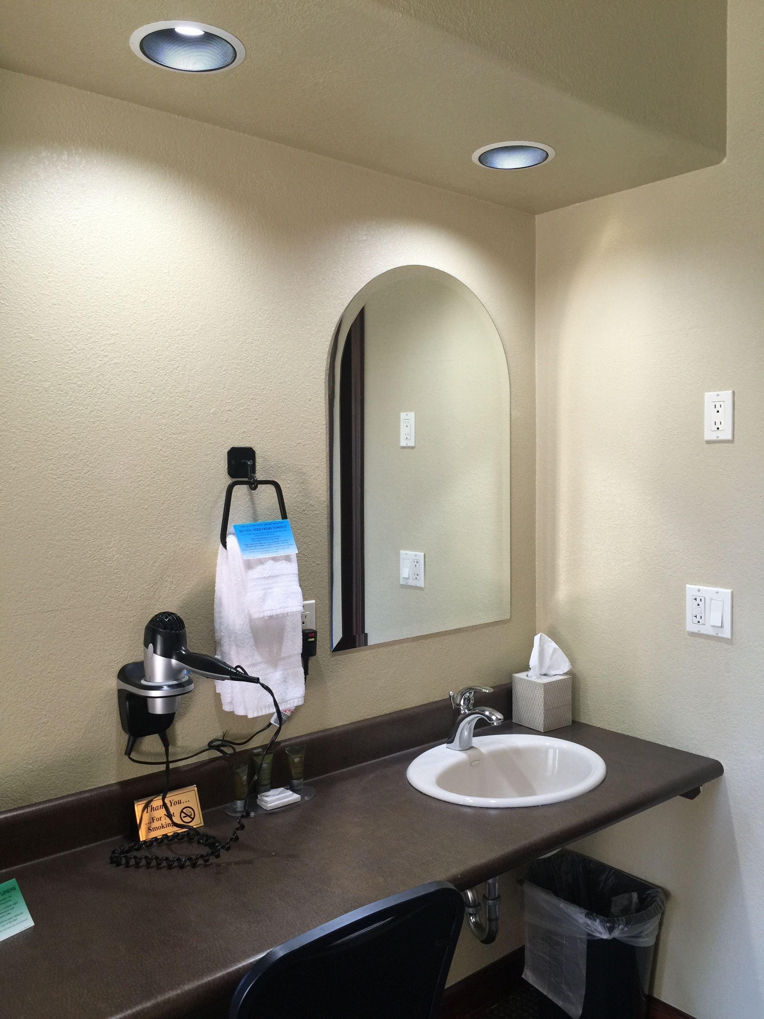 A hotel bathroom with a sink, mirror, towel rack, and a hairdryer.