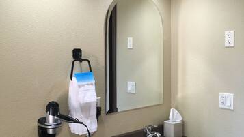 A hotel bathroom with a sink, mirror, towel rack, and a hairdryer.