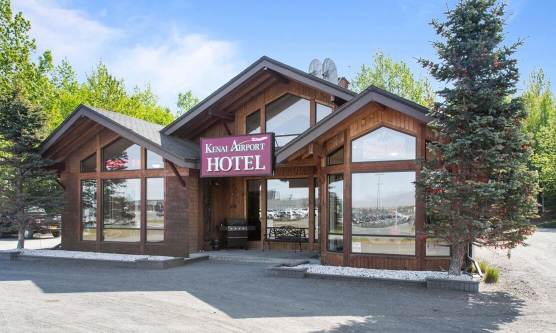 Ein Holzgebäude mit großen Fenstern, mit der Aufschrift Kenai Airport Hotel.