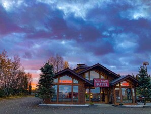 Un hôtel avec une enseigne bien visible indiquant « Kenai Airport Hotel » et un panneau indiquant qu’il y a des chambres disponibles.