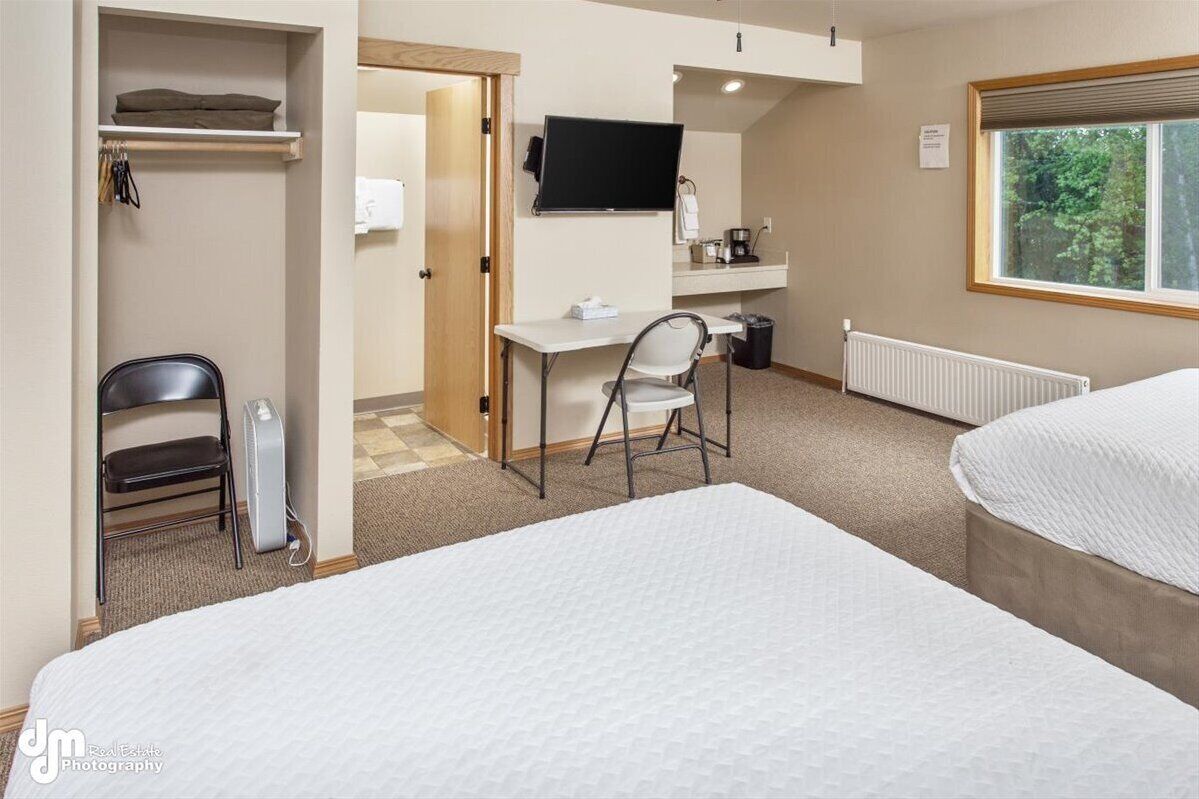 Una habitación de hotel con una cama, un escritorio con una silla, una televisión y una ventana.