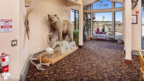 Un hall con un taxidermi de oso, un letrero de advertencia y un extintor.