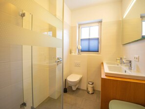 A modern bathroom with a glass shower enclosure, a toilet, a bidet, and a sink with a mirror above it. - Apartment near the ski slope in Brixen (Brixen im Thale)