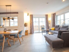 Un salon moderne avec un coin repas, de grandes fenêtres et un balcon.