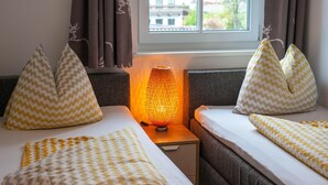 A hotel room with two beds, each with patterned pillows and a nightstand with a lamp. - Apartment near the ski slope in Brixen (Brixen im Thale)