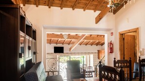 Un salon chaleureux avec un plafond en bois, un canapé, une table basse et un coin repas comprenant des chaises et une table.