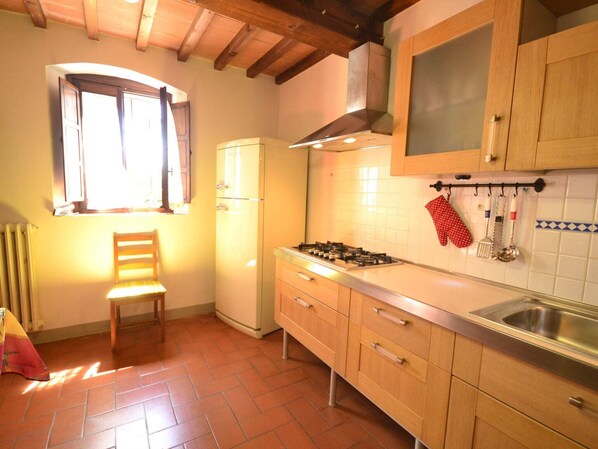 A kitchen with wooden cabinets, a gas stove, a window, and a radiator.