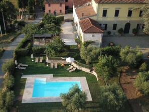 A residential property with a swimming pool, a patio with lounge chairs, and a garden.