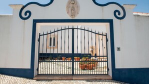 Une entrée fermée par un portail, agrémentée d’une arche décorative et surmontée des armoiries au-dessus de la porte.