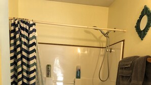 A bathroom with a shower, toilet, and sink. - Bird Creek Motel (Indian)