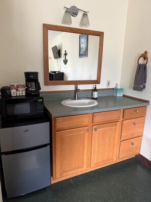 A compact kitchen with a microwave, coffee maker, and sink. - Bird Creek Motel (Indian)