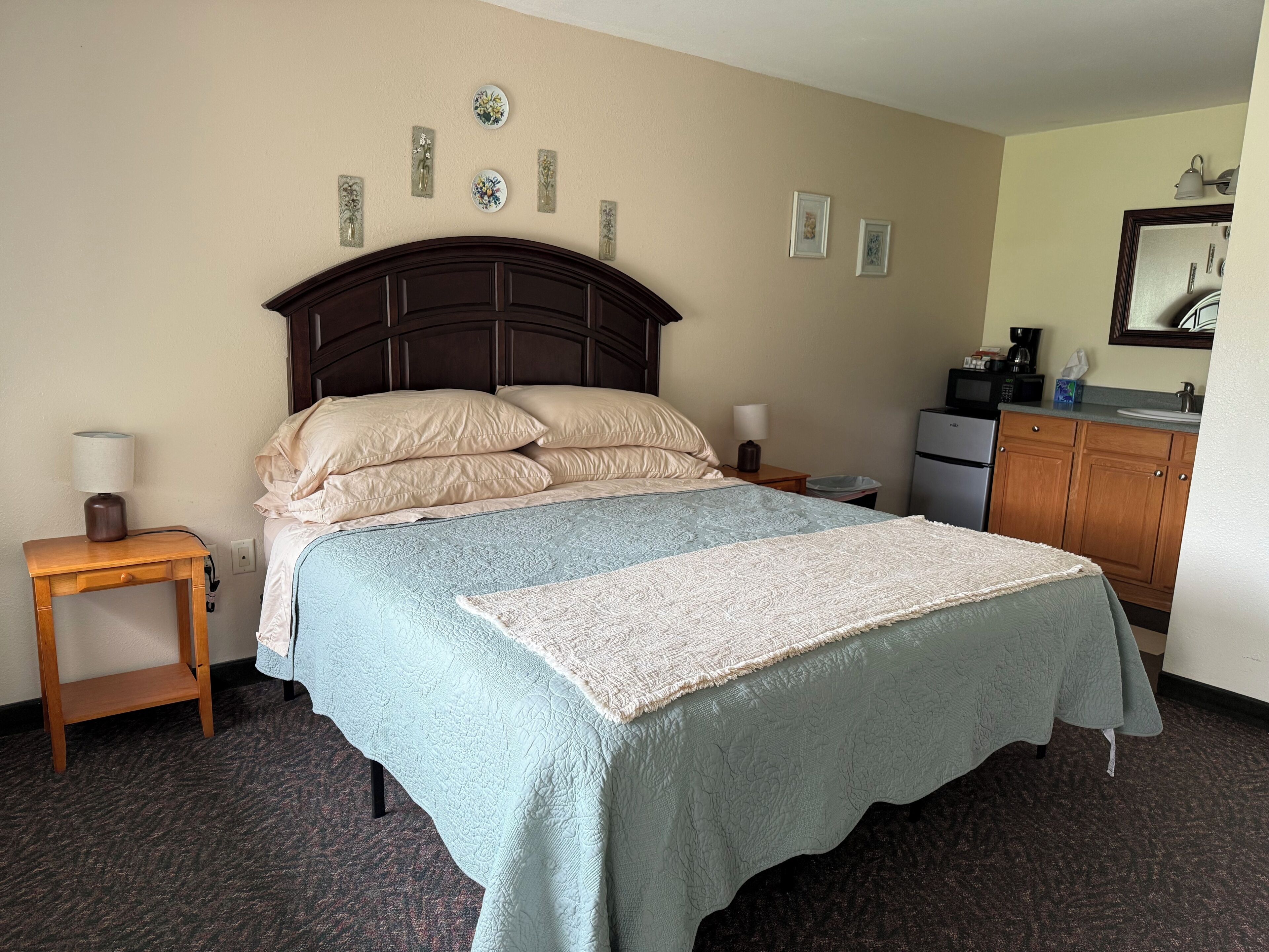 Ein Hotelzimmer mit Bett, Nachttischen, einem Schminktisch und Wandbildern.