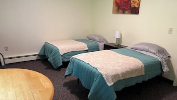 Een kamer met twee bedden, een ronde tafel en een schilderij aan de muur.