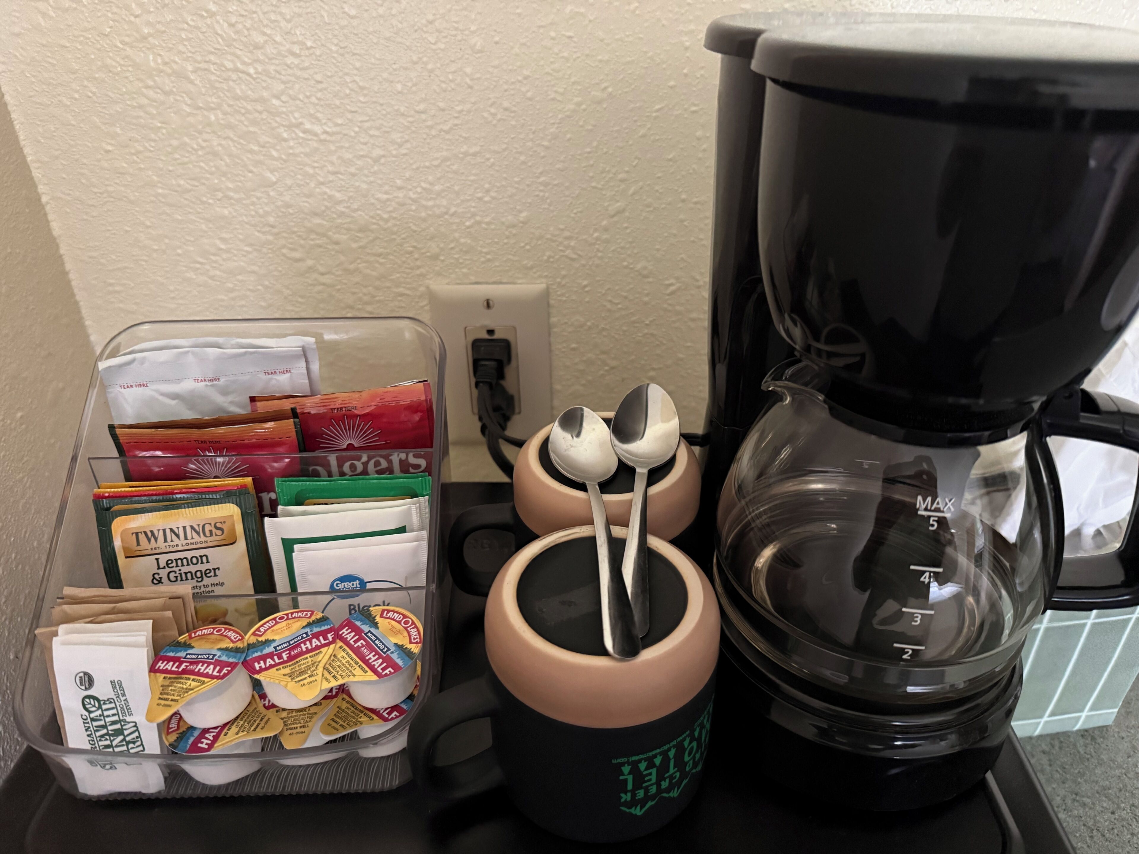 Una encimera de cocina con una cafetera, una taza y un recipiente con diversos alimentos.
