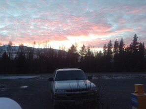 En bil parkeret på en parkeringsplads med skov og bjerge i baggrunden.