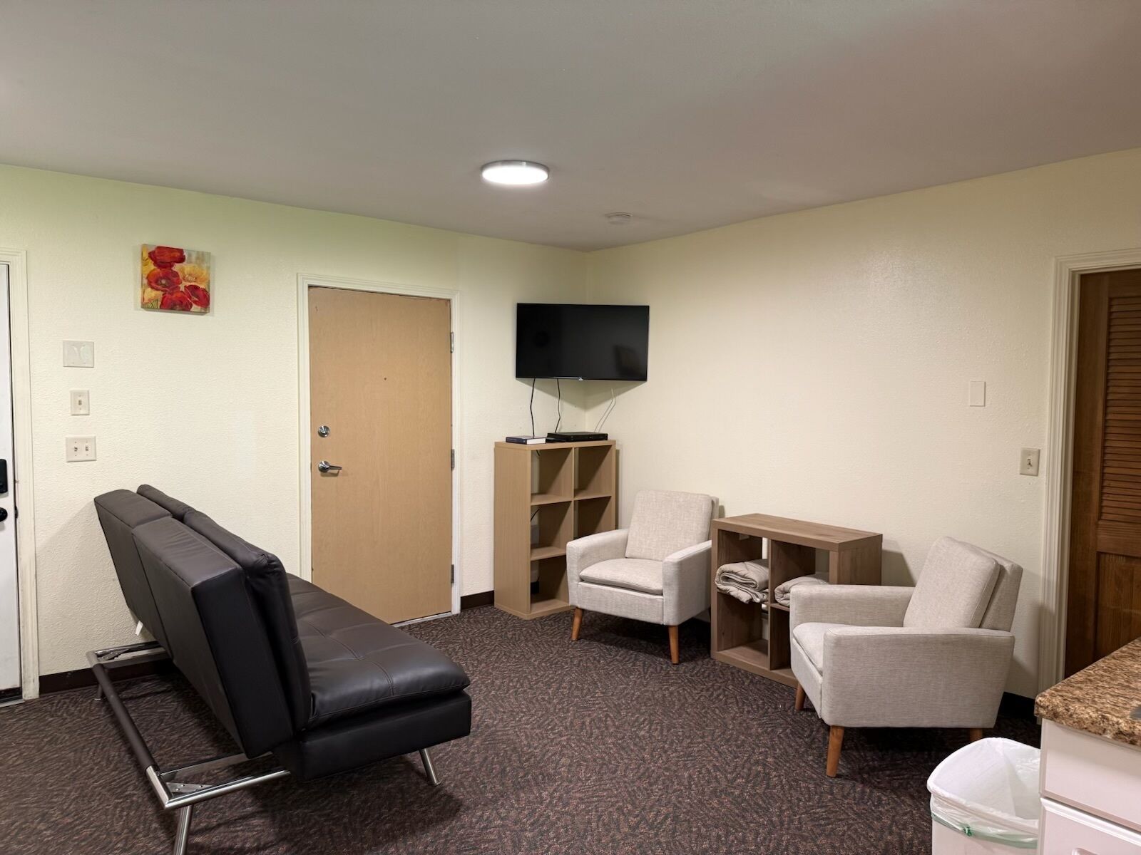 Ein Zimmer mit Massagegerät, zwei Sesseln, einem Fernseher und einem kleinen Holztisch.