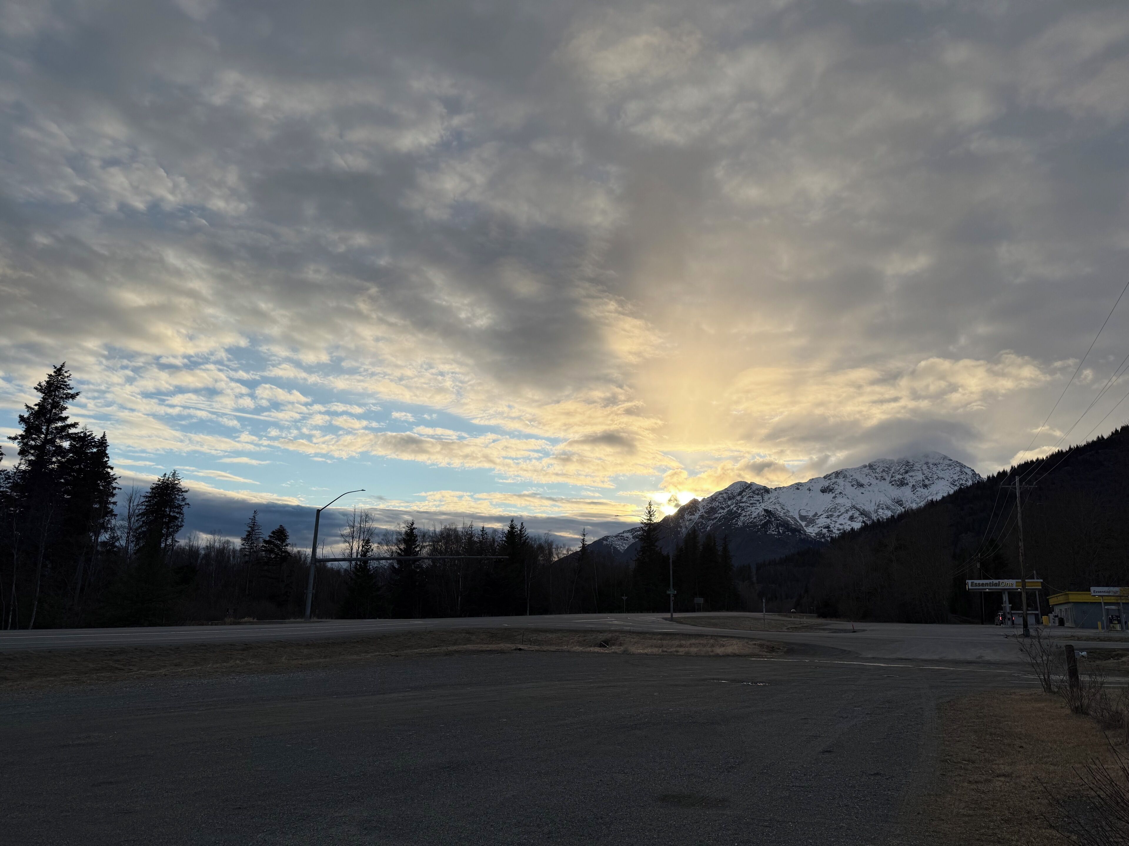 A road leading to a gas station with a mountain backdrop.