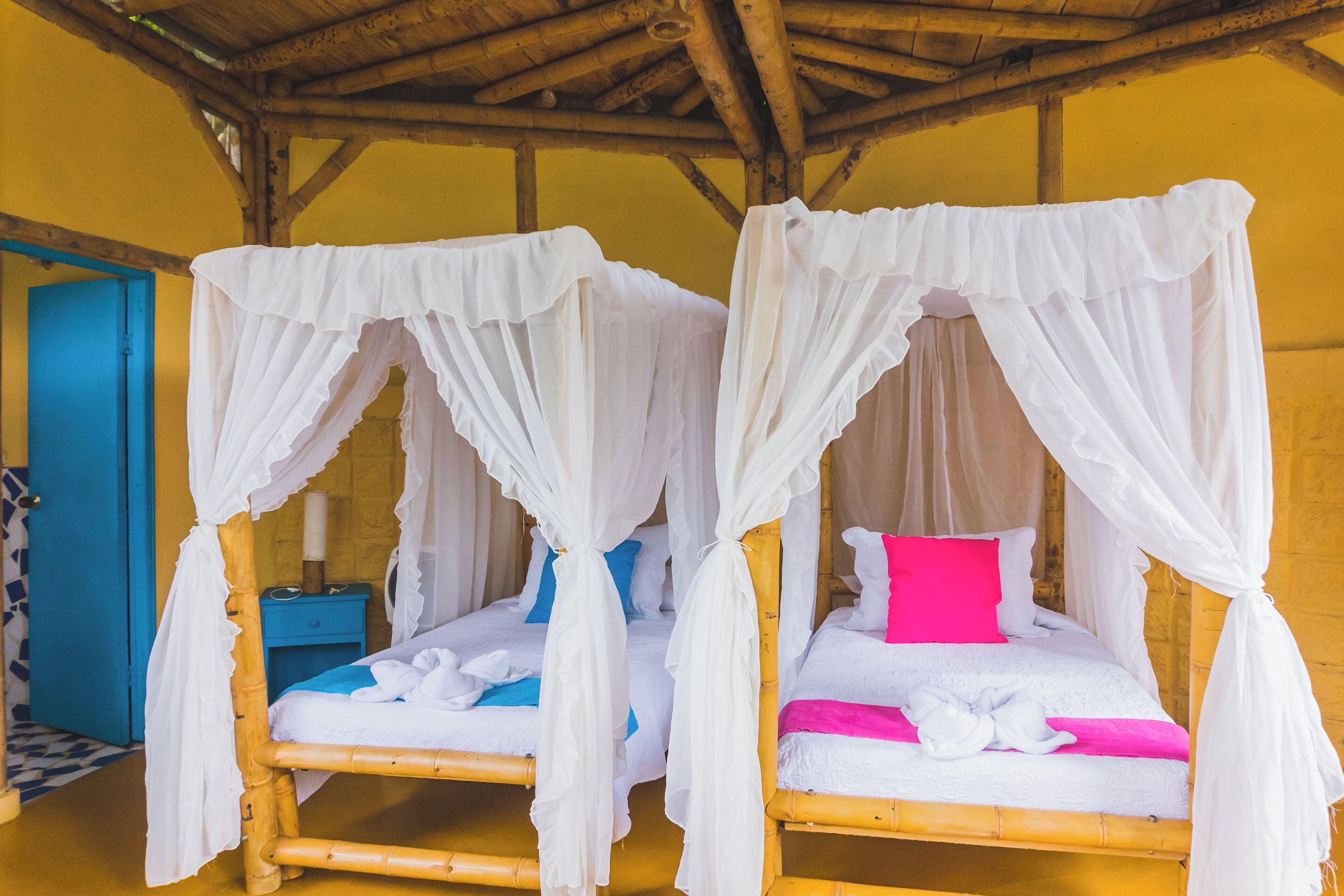 Two wooden beds with white canopies, a blue door, and a wooden ceiling.