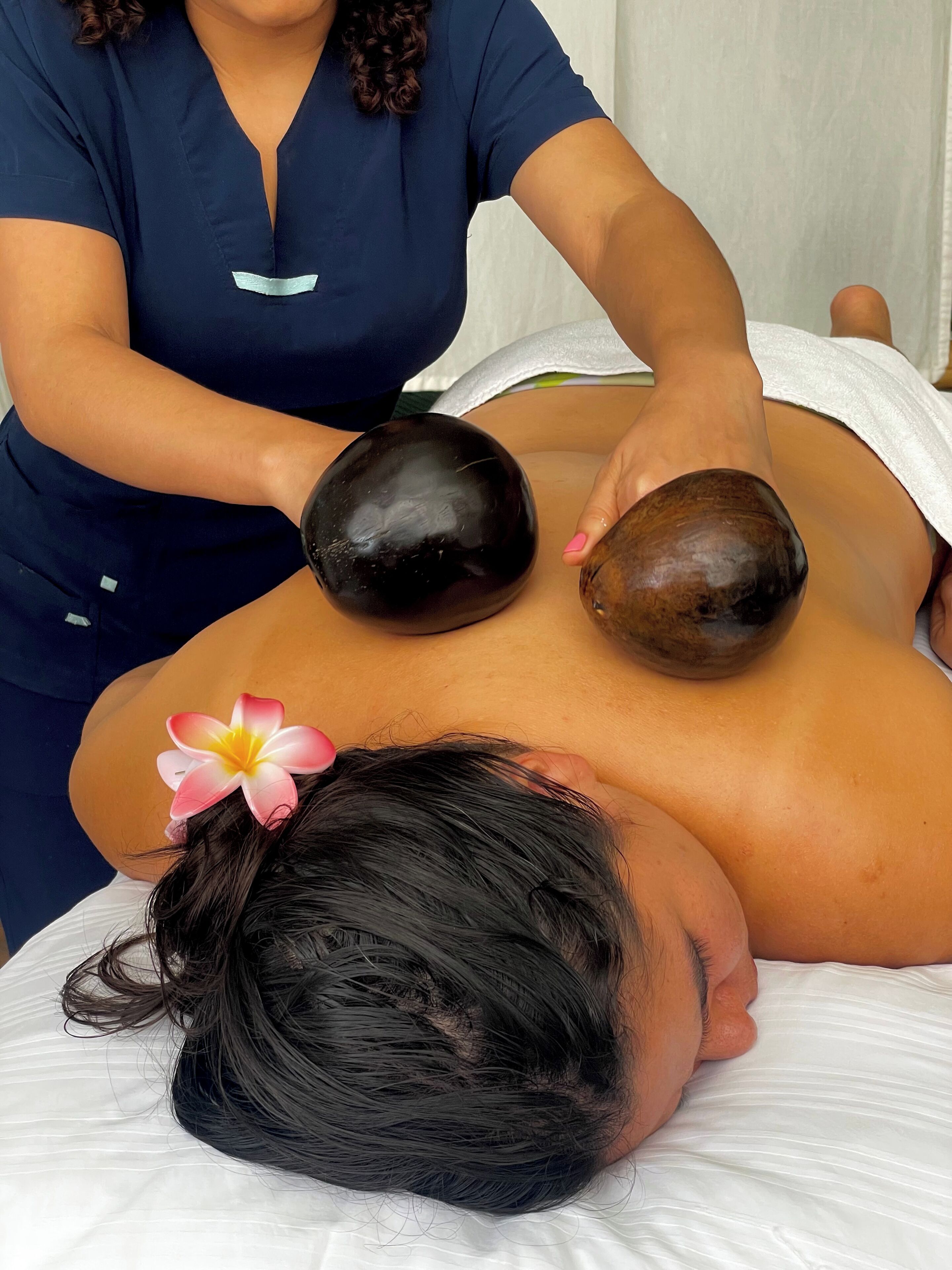 A massage therapy session with a person lying face down on a massage table, receiving a back massage from a therapist.