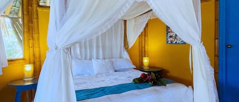 Ein Bett mit weißem Baldachin, eine blaue Bank und eine Wand mit einer gelben Tür.