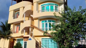 Un edificio de varios pisos con fachada curva, balcones con barandillas de vidrio y una escalera que conduce a los pisos superiores.