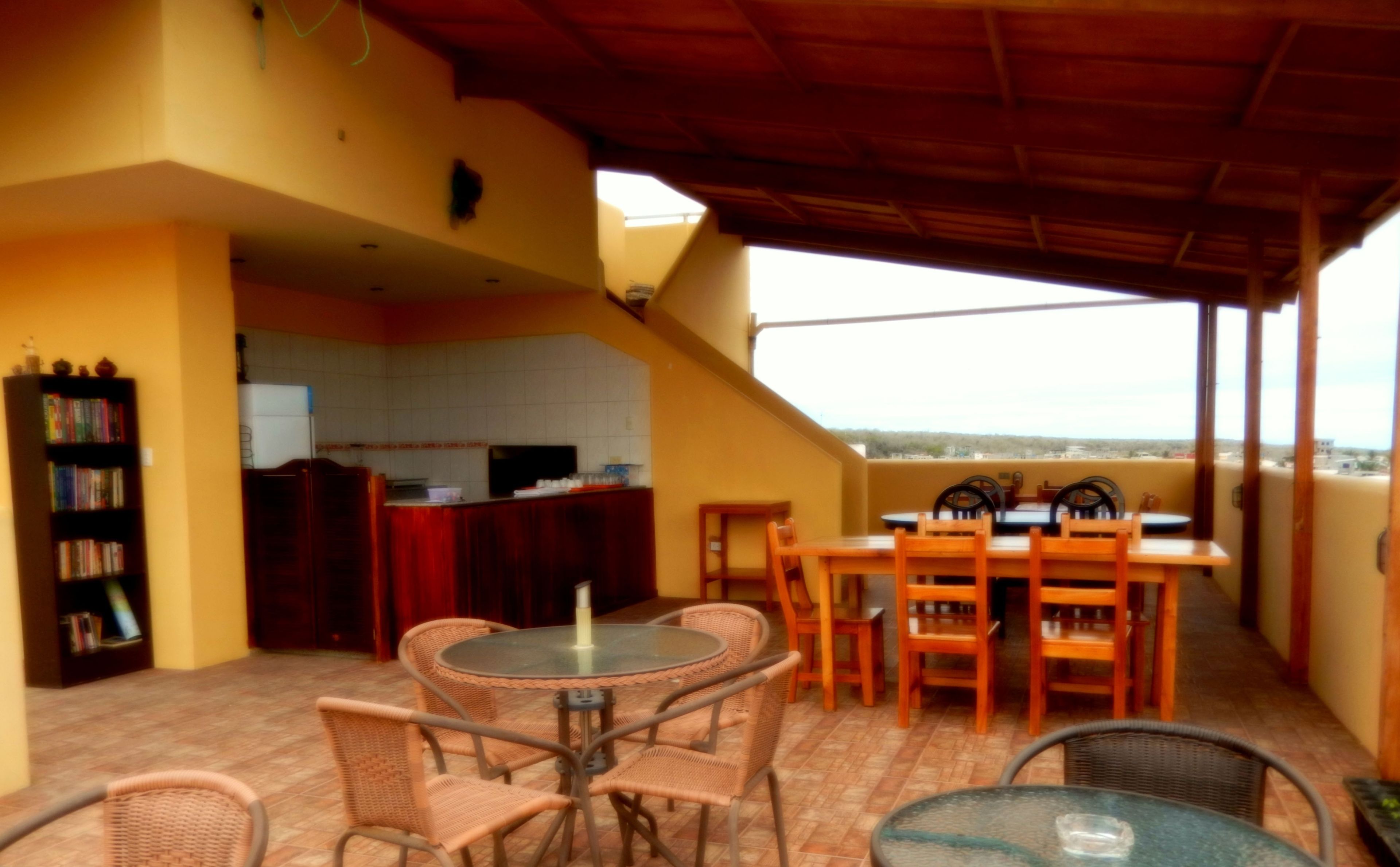 Un porche cubierto con una mesa y sillas, una estantería y una zona de cocina.