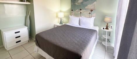 A neatly arranged bedroom with a bed, bedside tables, a lamp, and a painting on the wall.