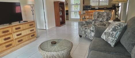 A living room with a television, sofa, and a dining area in the background.