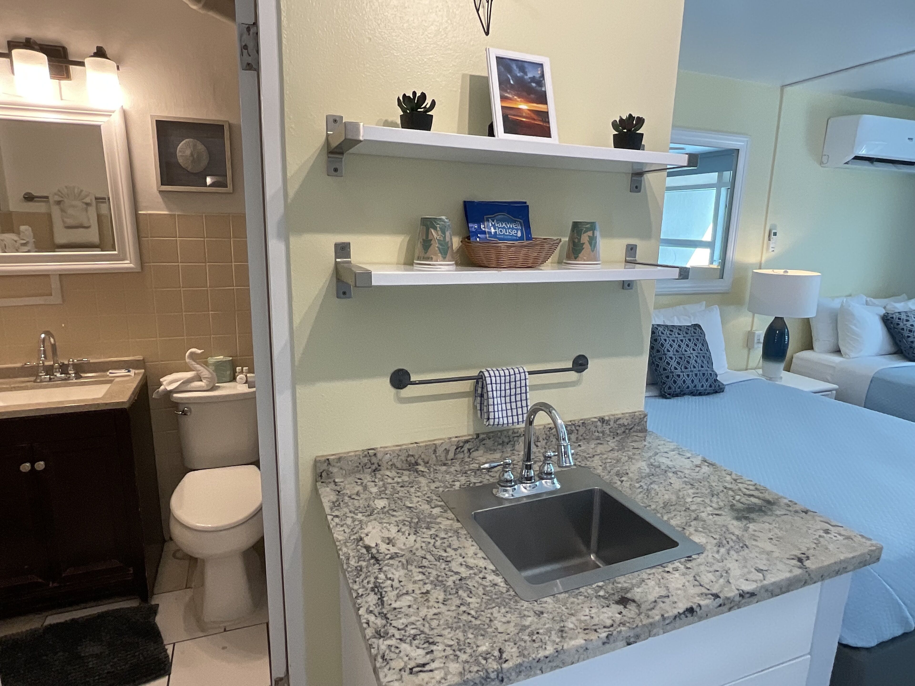 A modern bathroom with a sink, toilet, and a vanity. There are shelves above the sink with decorative items.