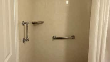 Una doccia con pavimento piastrellato, una porta bianca e un telo da doccia.
