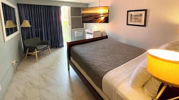 A hotel room with a bed, a desk, a chair, a TV, and a window with curtains.