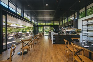 Un restaurante amplio con piso de madera, ventanas grandes y una zona de bar.