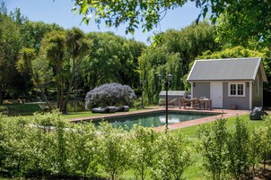 Una casa con piscina, rodeada de abundante vegetación y árboles.