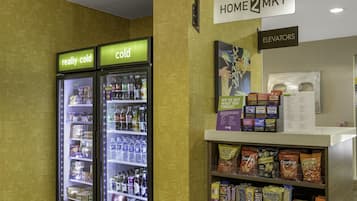 A vending area with snacks and beverages, a sign for elevators, and a wall with a pattern of text.