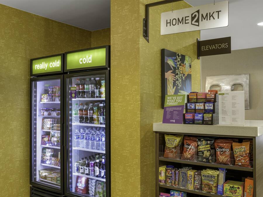 A vending area with snacks and beverages, a sign for elevators, and a wall with a pattern of text.