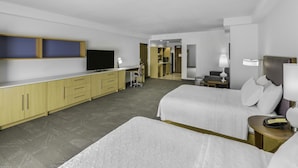 Una habitación de hotel con dos camas, un escritorio, un televisor y una kitchenette.