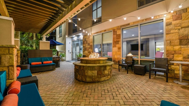Un patio al aire libre con un hogar a leña de piedra, asientos e iluminación colgante.